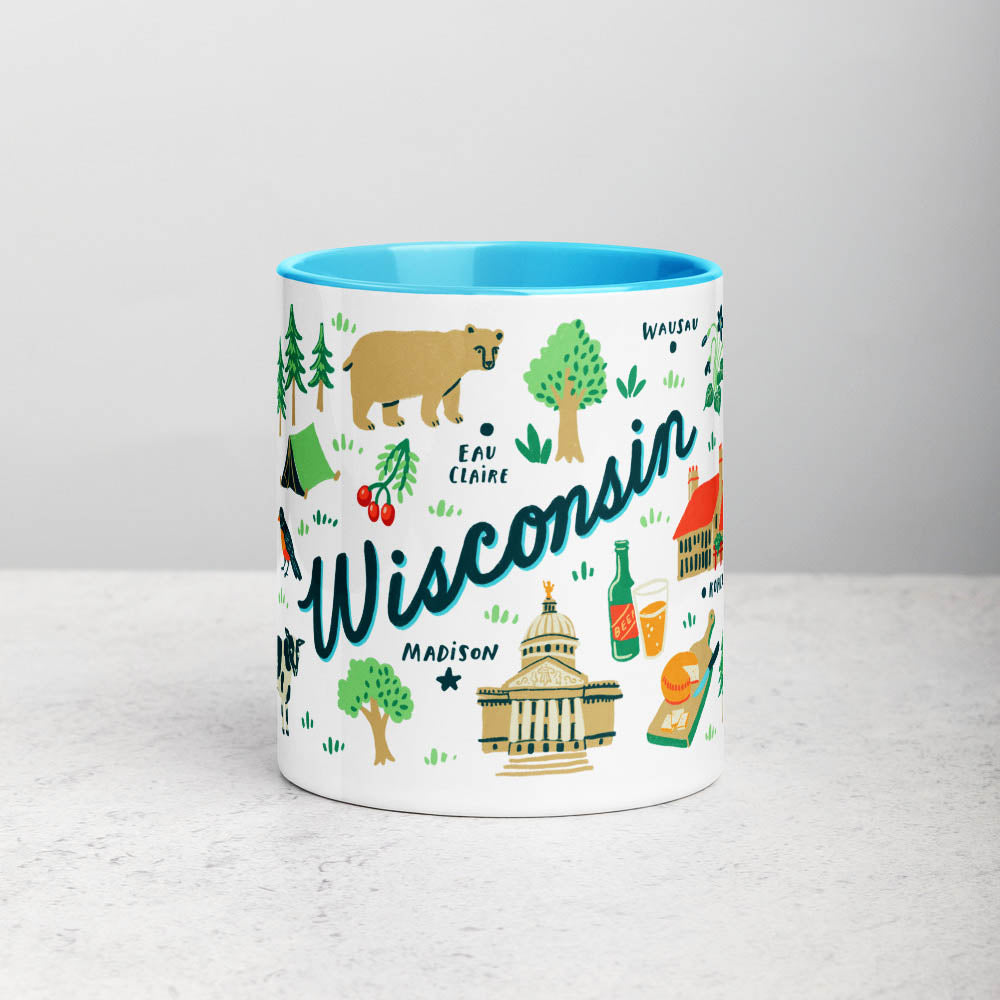 White ceramic coffee mug with blue handle and inside; has Wisconsin illustration by Angela Staehling